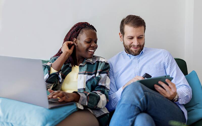 two people on sofa with laptop and tablet