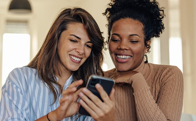 Two girls looking at mobile and smiling