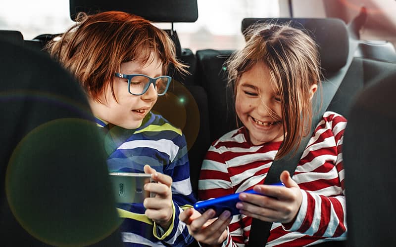 A boy and girl sitting in the car and wearing headphone